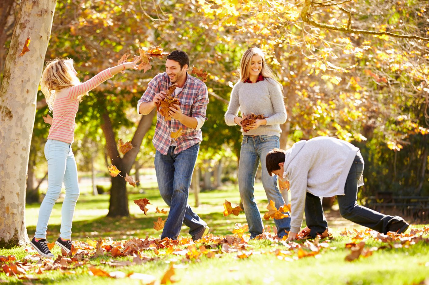 A family playing in autumn leaves